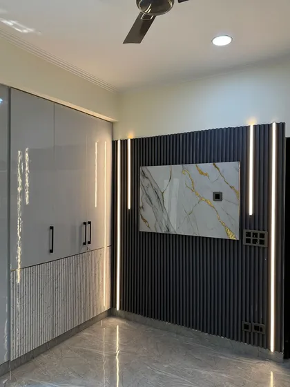 This image shows how the wardrobe design is integrated with the TV paneling, using similar materials and lighting to create a unified look in the bedroom.