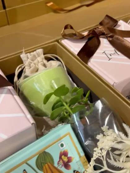 A close-up of the items inside our wellness hamper, including a small succulent, a scented candle, and a box of fine chocolates. These are perfect for promoting employee well-being.