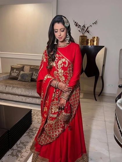 A full-length shot of the client, her regal red ensemble perfectly complemented by the makeup.