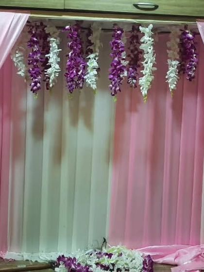 A very simple and elegant backdrop for a home Ganpati idol. The pink and white drapes with hanging purple flowers look beautiful in a small space.
