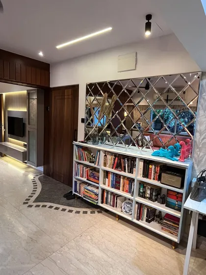 Another angle of the entryway, showing the relationship between the TV unit, the bookshelf with the diamond-patterned mirror, and the unique floor tile inlay that guides you into the home.