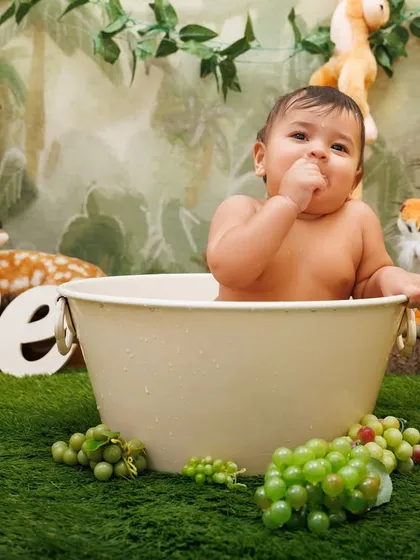 A cute baby boy enjoying his tub splash session, surrounded by grapes and jungle animals.