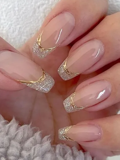 A glamorous take on the French manicure with a square shape and a sparkling silver glitter tip outlined in gold.