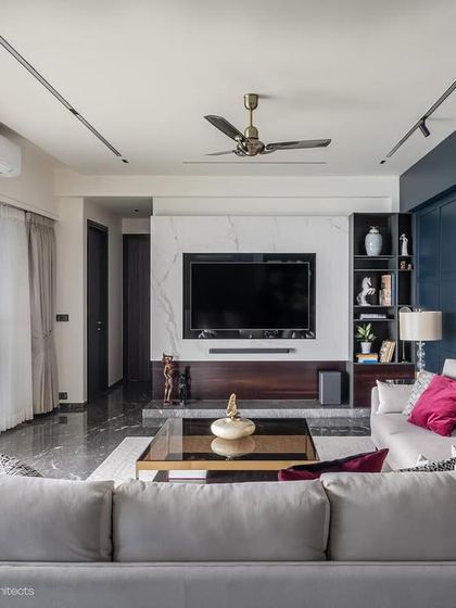 A wide view of the Maloo Residence living room, showing how we balance different elements. The dark marble floor grounds the space, while the bright white TV unit and light-colored sofa keep it feeling open and spacious.