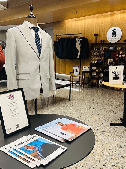 The setup for our KPMG trunk show, featuring a finished light grey suit on a mannequin. This display serves as a tangible example of our craftsmanship and provides a focal point for discussions on fit, fabric, and style.