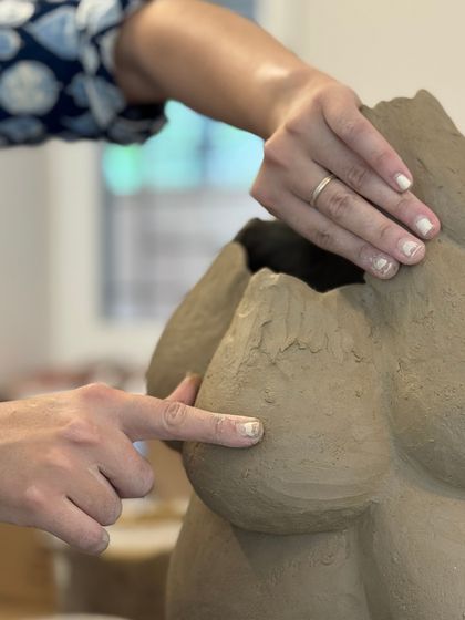 A close up of hands working on a large, sculptural hand built piece, demonstrating the tactile and intuitive nature of the process.
