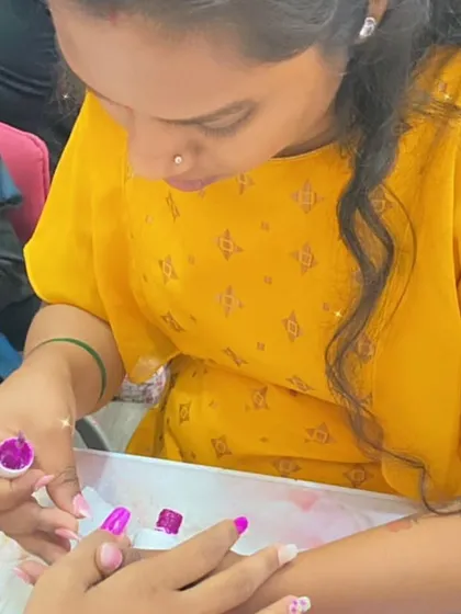 A student practices applying a vibrant magenta polish, focusing on her brush control and even application.