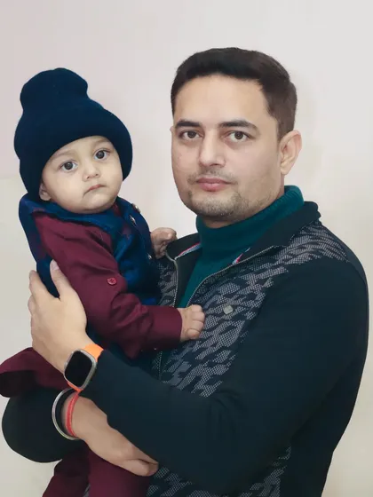 A father and his baby, dressed in matching color tones, pose for a portrait. This photo has a calm and loving feel.