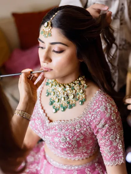 A behind-the-scenes shot of the "pink fairy" bride. Here, I'm applying the final touches to her lip color, ensuring it perfectly matches her pink lehenga.