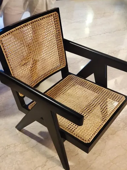 A close-up of the iconic Pierre Jeanneret-inspired lounge chair, showing the flawless black finish on solid teak and the intricate hand-woven cane seat and back. This design is a cornerstone of my mid-century modern collection.