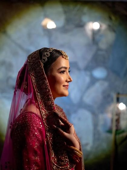 A dramatic portrait of the bride, with a spotlight creating a halo effect against a dark, textured background.