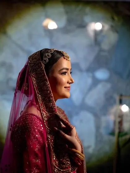 A dramatic portrait of the bride, with a spotlight creating a halo effect against a dark, textured background.