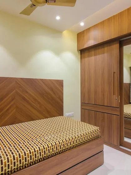 The sliding wardrobe in this wooden-themed bedroom includes a mirror panel, which helps make the space feel larger.