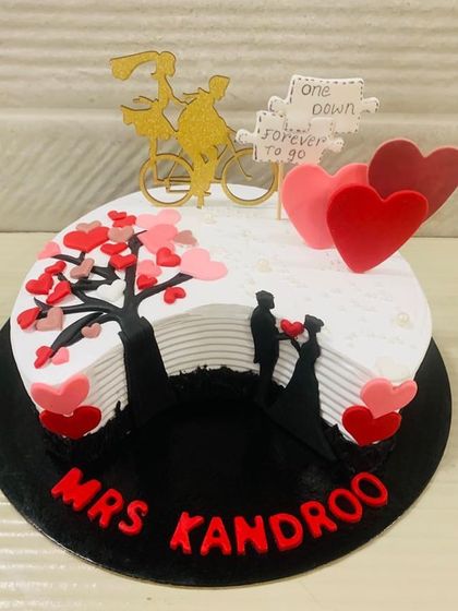 A sweet and romantic anniversary cake telling a love story. It features a silhouette of a couple under a tree of hearts and a topper that says "one down, forever to go."