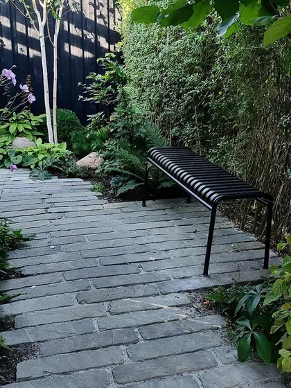 A simple, elegant bench placed along a garden path offers a resting spot to enjoy the view. We design pathways that are not just for transit but also for experiencing the garden from different perspectives.