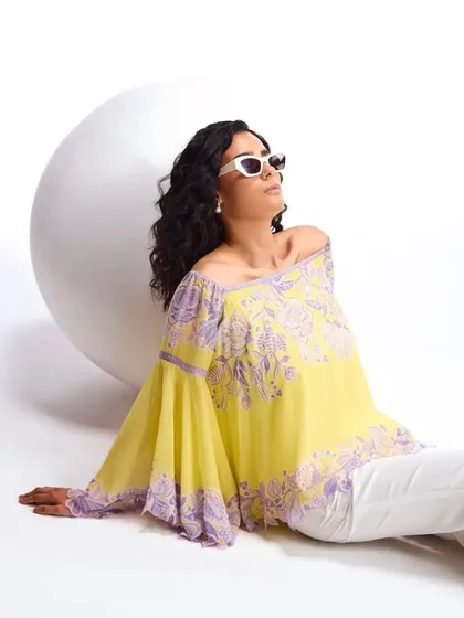 A chic off-shoulder top in yellow and lavender, perfect for pairing with white trousers for a summer day out.