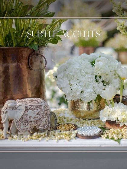 Subtle Accents. A beautifully carved elephant figurine sits amongst fresh white hydrangeas and traditional copper pots.