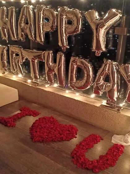 A close-up of the personal touches in our balcony birthday decoration. We used silver foil 'Happy Birthday' balloons against a wall of fairy lights and spelled out 'I ❤️ U' with red rose petals on the floor.