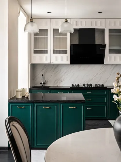 The kitchen at Riviera Maison features a bold color choice with deep emerald green lower cabinets. We contrasted this with white upper cabinets with fluted glass, a marble backsplash, and a black countertop for a look that is both classic and modern.