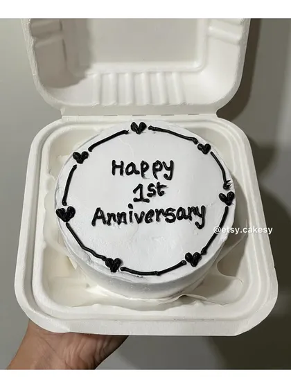 A classic black and white bento cake design for a 'Happy 1st Anniversary' celebration.