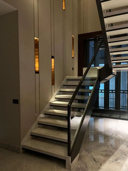 This view of the geometric staircase highlights the integrated wall lighting. Vertical slits of warm light create a rhythm along the wall, guiding the way and adding to the architectural drama.
