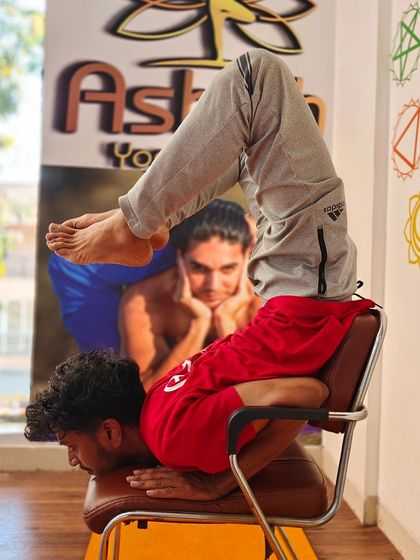 A complex inversion and backbend combination performed on a chair, showcasing mastery of balance and flexibility.