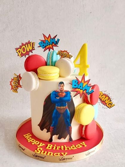 A Superman-themed cake for Sunay's 4th birthday, decorated with colourful macarons and comic book-style action words.