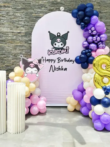 A cute and edgy Kuromi-themed 8th birthday. The pastel purple backdrop is decorated with a purple, blue, and pink balloon garland and a large gold foil number '8'.