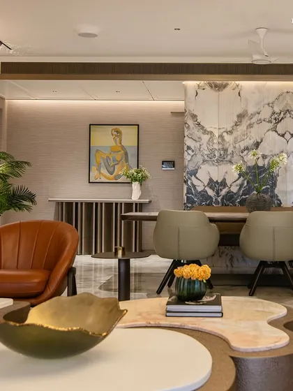 A detail shot of the living area, where a leather armchair and curated art pieces punctuate the space. The design uses Italian marble floors and limewash-finished walls to set a quiet, sophisticated tone, turning a simple transition into a refined prelude.