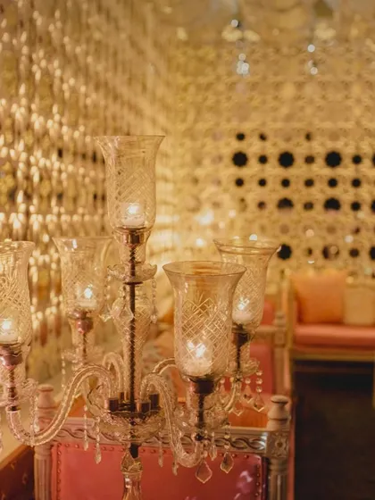 Details matter in luxury decor. This close-up shows a crystal candelabra against the backdrop of our Sheesh Mahal mirror-work panels, reflecting the warm candlelight to create a truly magical and opulent effect.