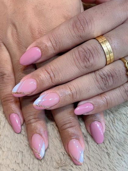 A beautiful example of subtle elegance. This manicure features a soft pink base with delicate white and gold glitter swirls on the accent nails.