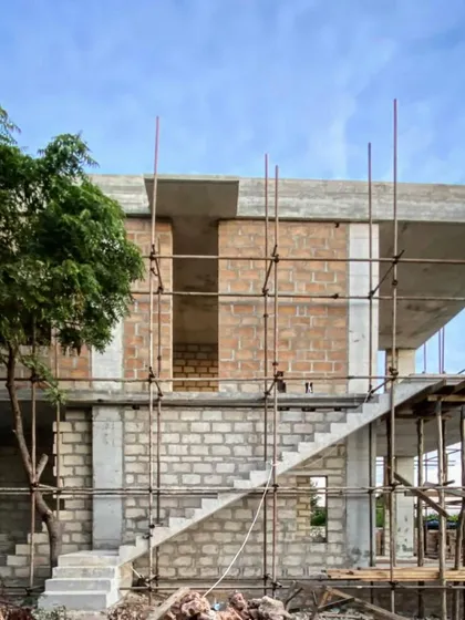 A view of the concrete and blockwork structure at Kizikula, with a tree growing through the frame. We often design around existing natural features, integrating them into the architecture itself.
