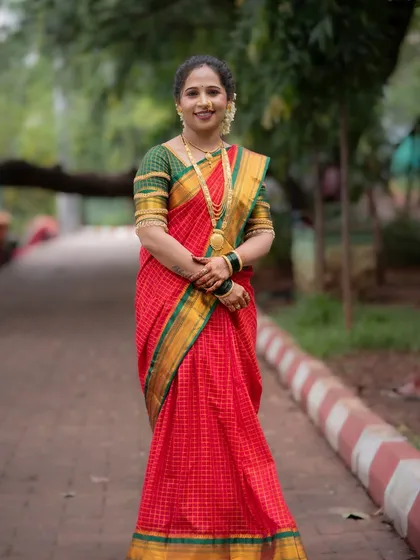 A full-length portrait of a woman in a beautiful red and green saree, celebrating Vat Purnima. Her confident and happy pose perfectly captures the festive spirit.