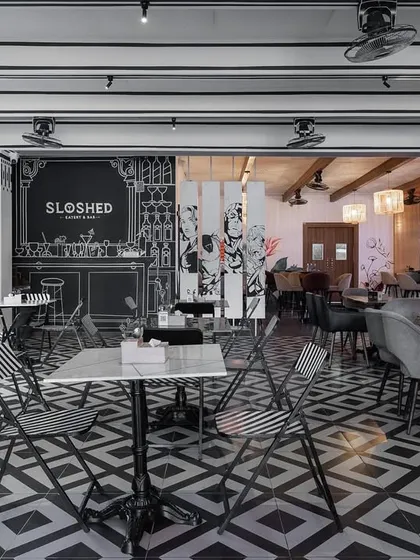 Another perspective of the sketch cafe, showing the contrast between the white brick wall and the bold, graphic floor. The design is a playful take on reality, creating a memorable and unique dining experience.