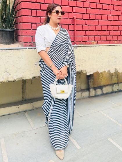The vertical stripes of this saree create a wonderfully elongating effect. Paired with a crisp white shirt-blouse, it's a powerful look that is both professional and stylish.