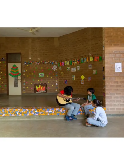 Students find a space for creative expression on the mosaic-tiled stage at Buddhi School in Bengaluru. We design learning environments to be joyful and interactive, using warm, natural materials like earth blocks to create inviting spaces for children.