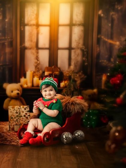 This little elf is ready for Christmas, sitting in a sleigh in a cozy, warmly lit room filled with presents and holiday cheer.