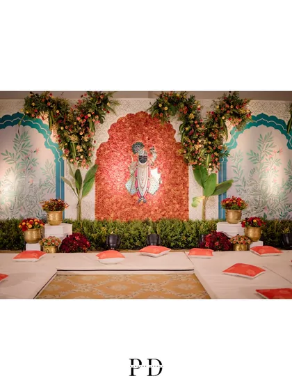 The stage for the Sagai and Mandap Muhurat, featuring a floral backdrop of Lord Shrinathji. The design combines traditional motifs with lush greenery for a fresh and sacred ambiance.