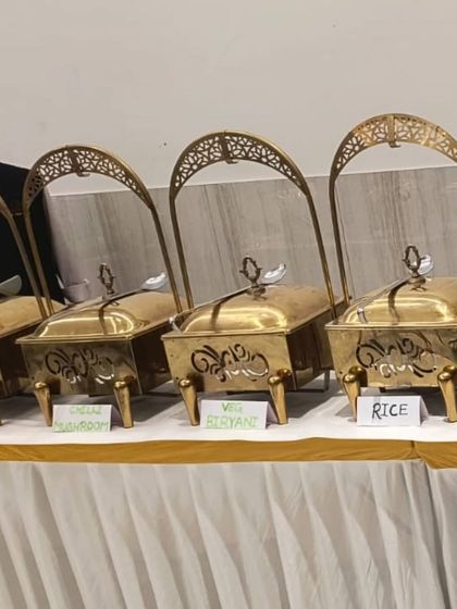 A close-up of our ornate serving dishes, labeled with menu items like Veg Hakka Noodles and Chilli Mushroom. Clear labeling helps guests easily identify their choices.