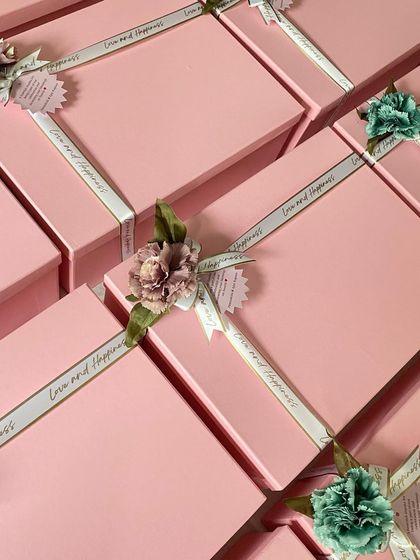 A different view of our elegant pink packaging for a bulk return favor order. The combination of two soft colors, custom ribbons, and floral toppers creates a sophisticated and cohesive look for any event.