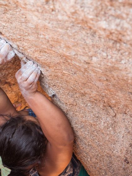 A close-up of a climber's hands on the rock in Hampi. This image shows the determination and grip strength developed through bouldering.