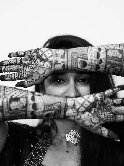 A powerful black and white close-up, where the intricate mehendi patterns frame the bride's expressive eyes.