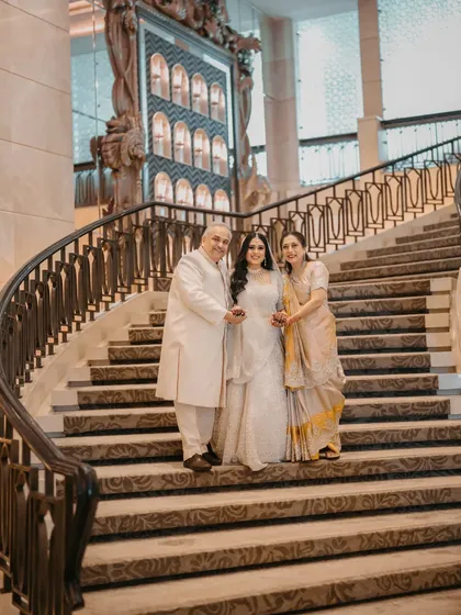 A formal family portrait on the staircase, capturing the grace and elegance of the bride with her parents.