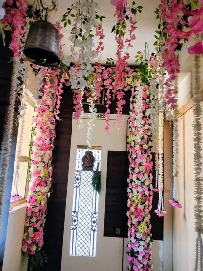 We created a dreamy wedding corridor using hanging garlands of pink and white flowers. This design transforms a simple passageway into a beautiful floral canopy, complete with a traditional bell at the entrance.