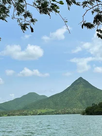 A serene view of a lake with a sharp mountain peak in the background.