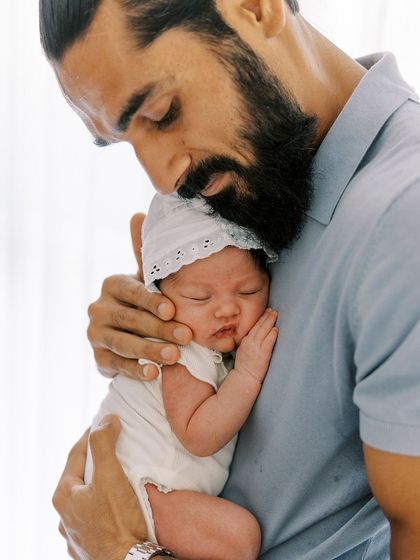 A father's tender embrace. This close-up shot of a dad holding his sleeping newborn is full of warmth and emotion.