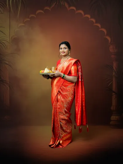 This full-length portrait showcases the elegance of a mom-to-be in a vibrant red saree. Holding a traditional thali, she embodies grace and cultural pride in our custom studio setting.
