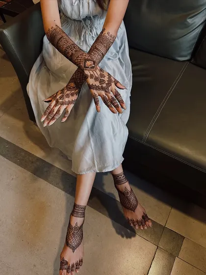 A complete bridal look involves adorning both hands and feet. Here you can see how the intricate patterns on the arms are complemented by the elegant designs on the feet, creating a cohesive and breathtaking effect.