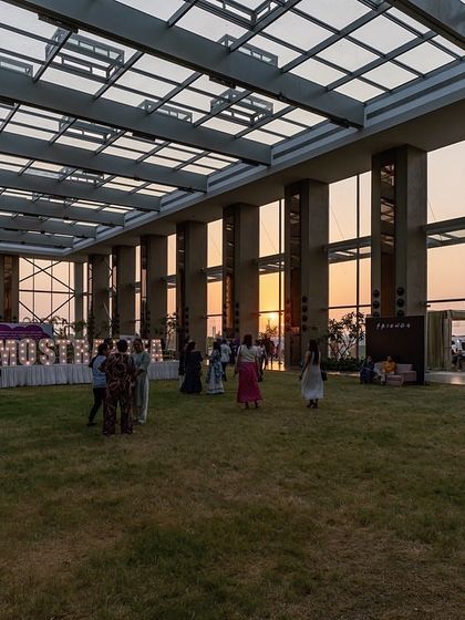 The sun sets through the transparent walls of the Glass Pavilion during an event. The design was intended to capture natural light and create a dynamic interplay between the interior, the sky, and the surrounding landscape.