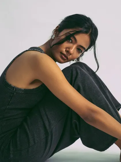 A relaxed, grounded pose. The simplicity of the outfit and the background keeps the focus entirely on the model's mood.